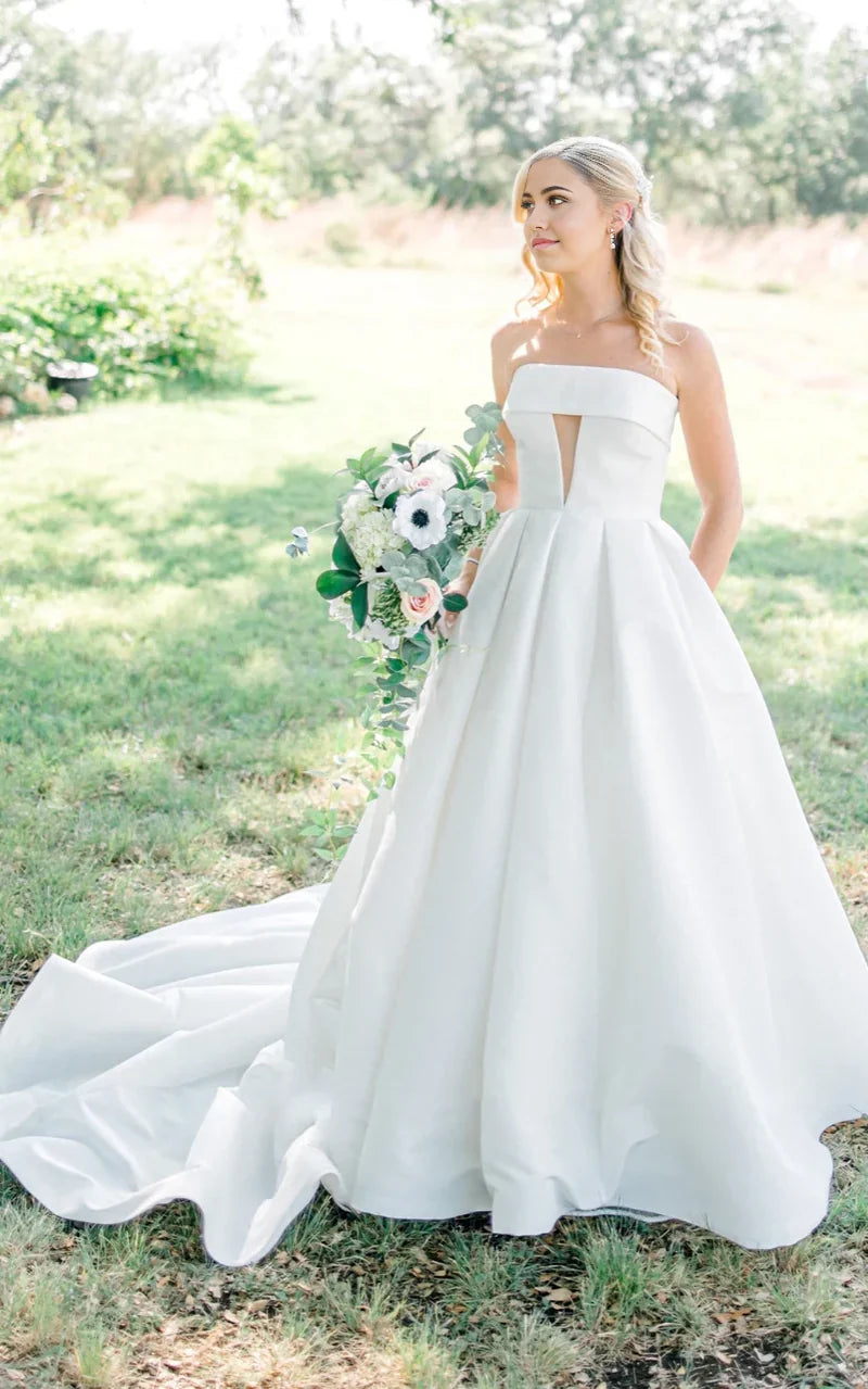 Vestido de novia elegante de satén con corte A, sin tirantes, espalda abotonada y cola capilla para playa